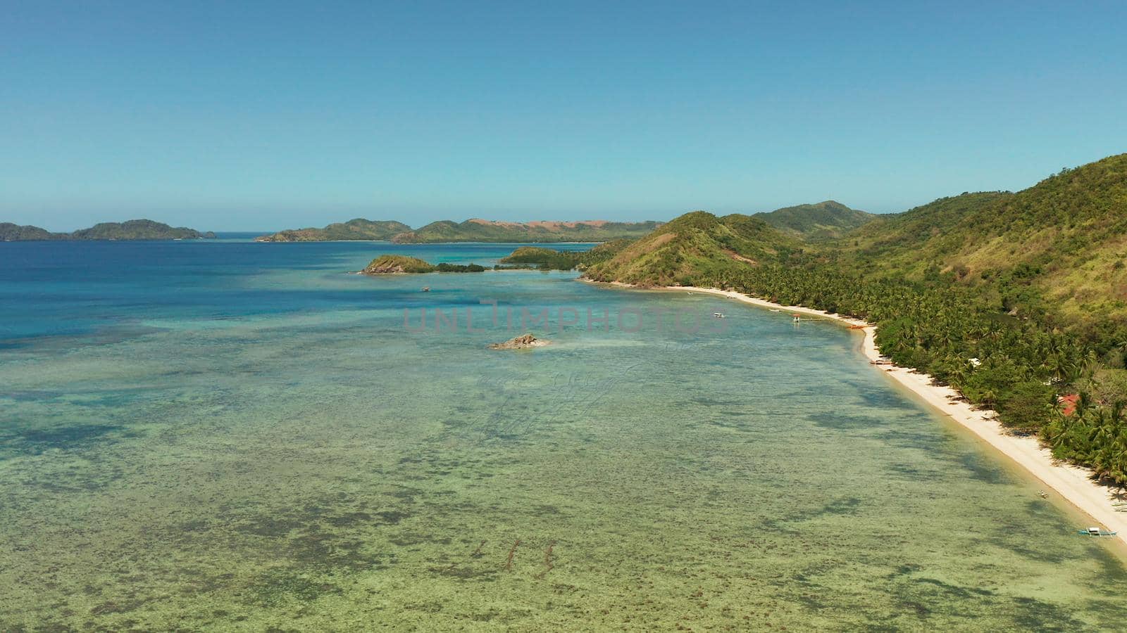 Aerial view tropical island with beach, coral reef and blue lagoon. Busuanga, Palawan, Philippines. Seascape island and clear blue water tropical landscape