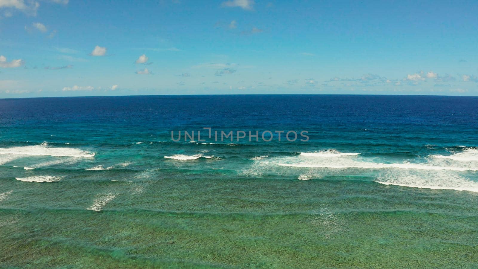 Seascape: blue ocean and surf waves crashing on a coral reef top view. Summer and travel vacation concept