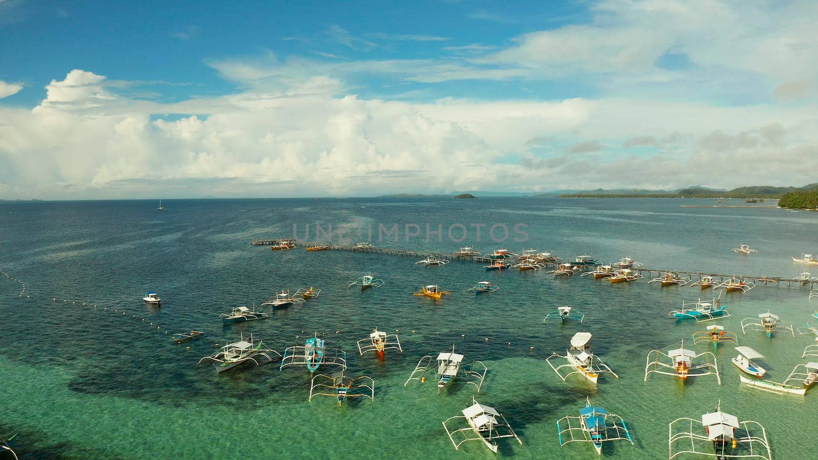 Tourist boats moored to a long pier on a tropical island, General Luna, Siargao.