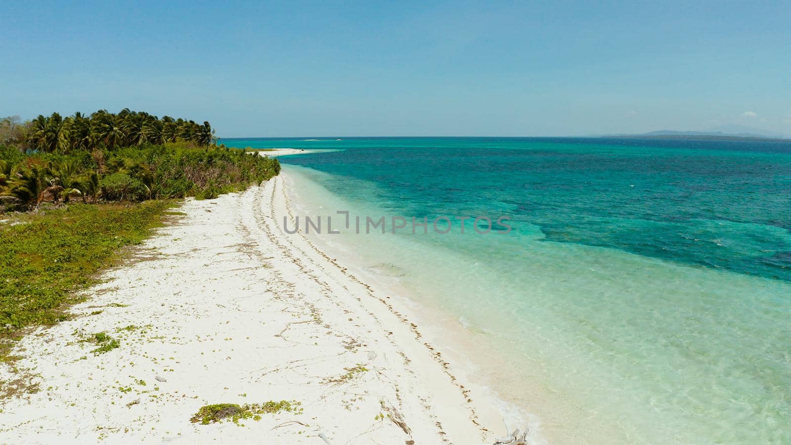 White sandy beach with turquoise water by atoll coral reef and blue sea, aerial view. Small island Canimeran with sandy beach. Summer and travel vacation concept. Balabac, Palawan, Philippines.