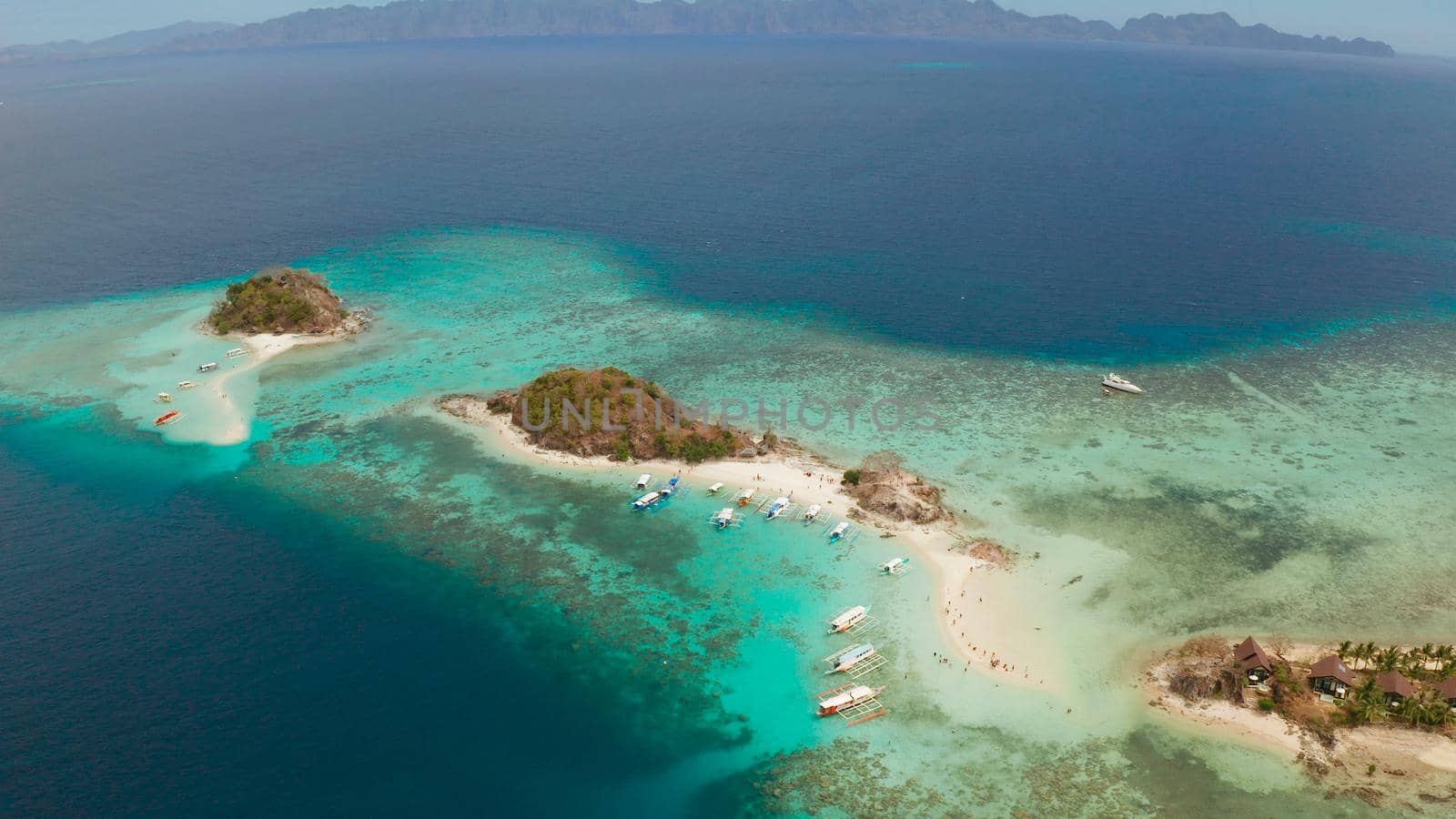 aerial seascape bay with tropical island and sand beach, turquoise water and coral reef. Bulog Dos, Philippines, Palawan. tourist boats on coast tropical island.