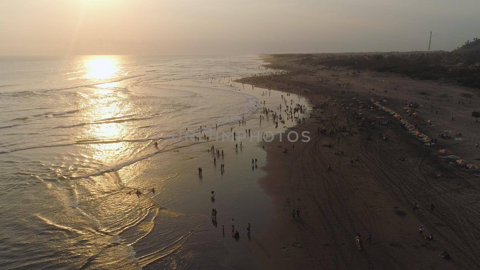 sandy beach parangtritis near ocean with big waves, people in tropical resort at sunset. Yogyakarta, Indonesia. aerial view seascape, ocean and beautiful beach. Travel concept. Indonesia, jawa