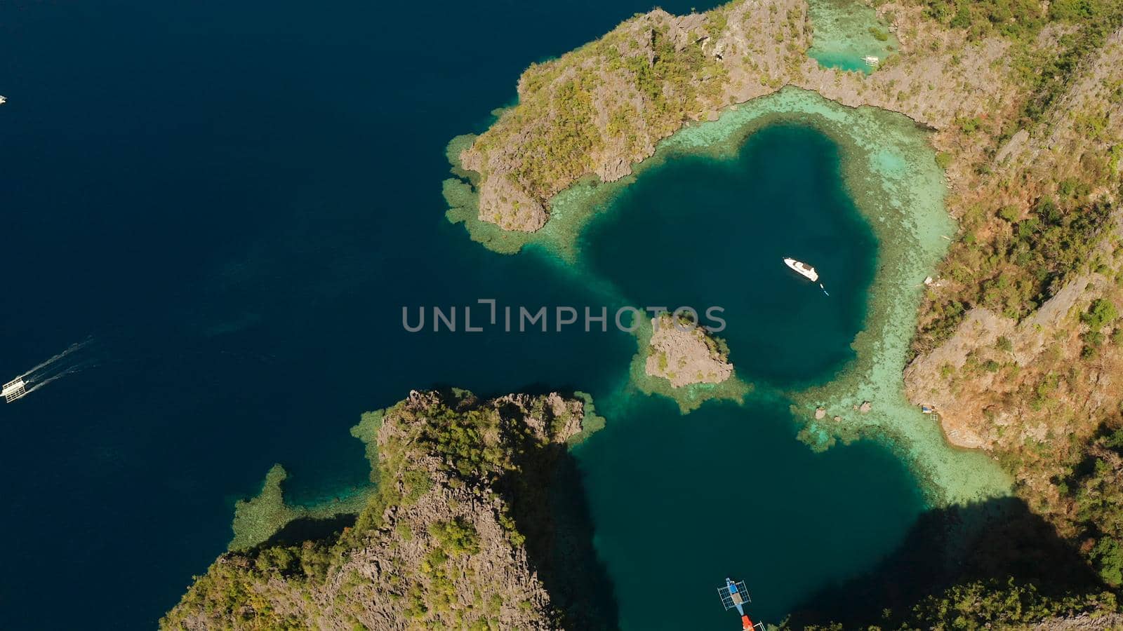 Aerial drone speed boat with tourists in beautiful lagoon. lagoons and coves with blue water among the rocks. Seascape, tropical landscape. Palawan, Philippines, Busuanga