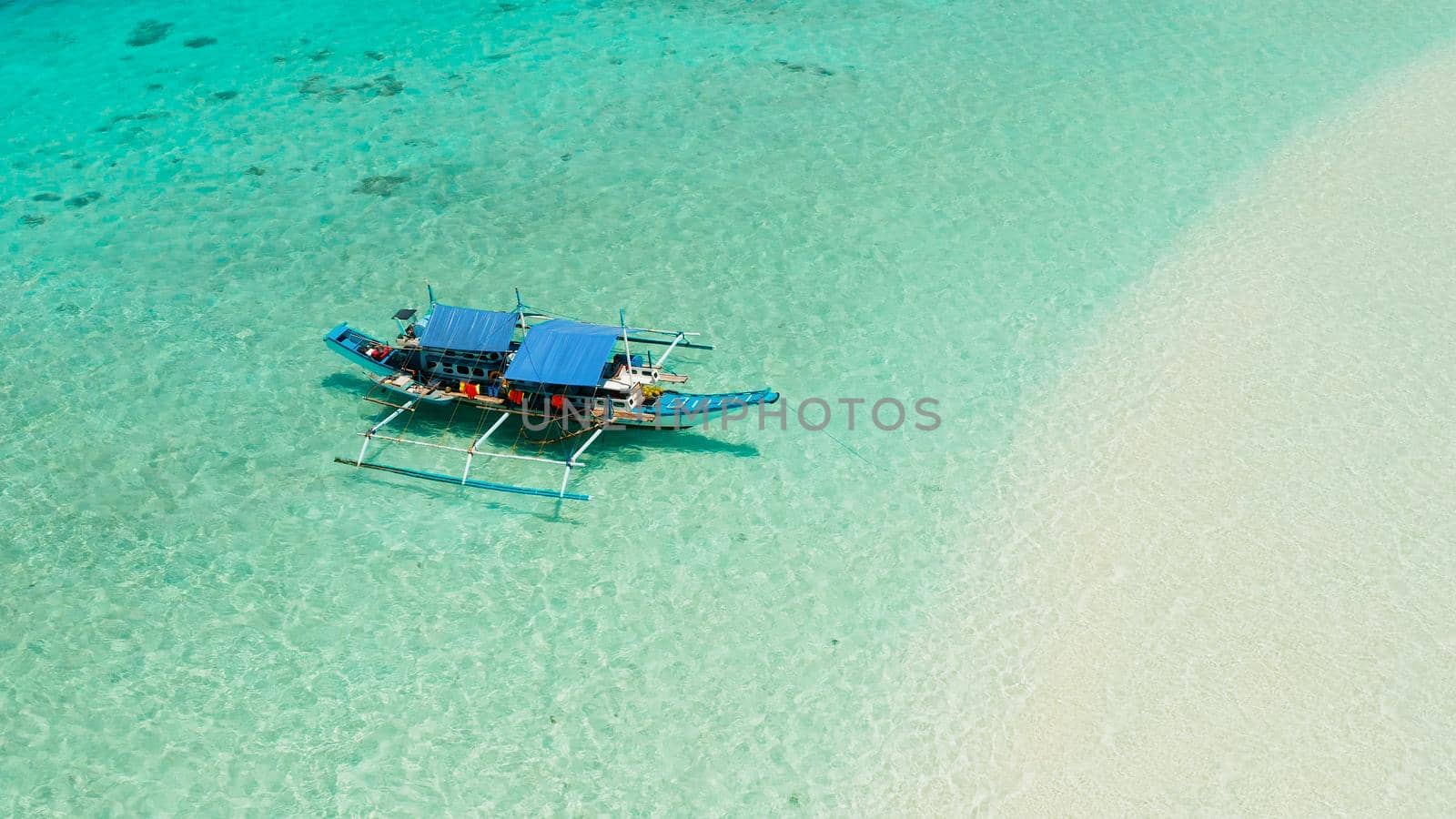 Boat on a tropical beach in the turquoise water of the lagoon from above. Summer and travel vacation concept. Mansalangan sandbar. Beach at the atoll. Balabac, Palawan, Philippines.