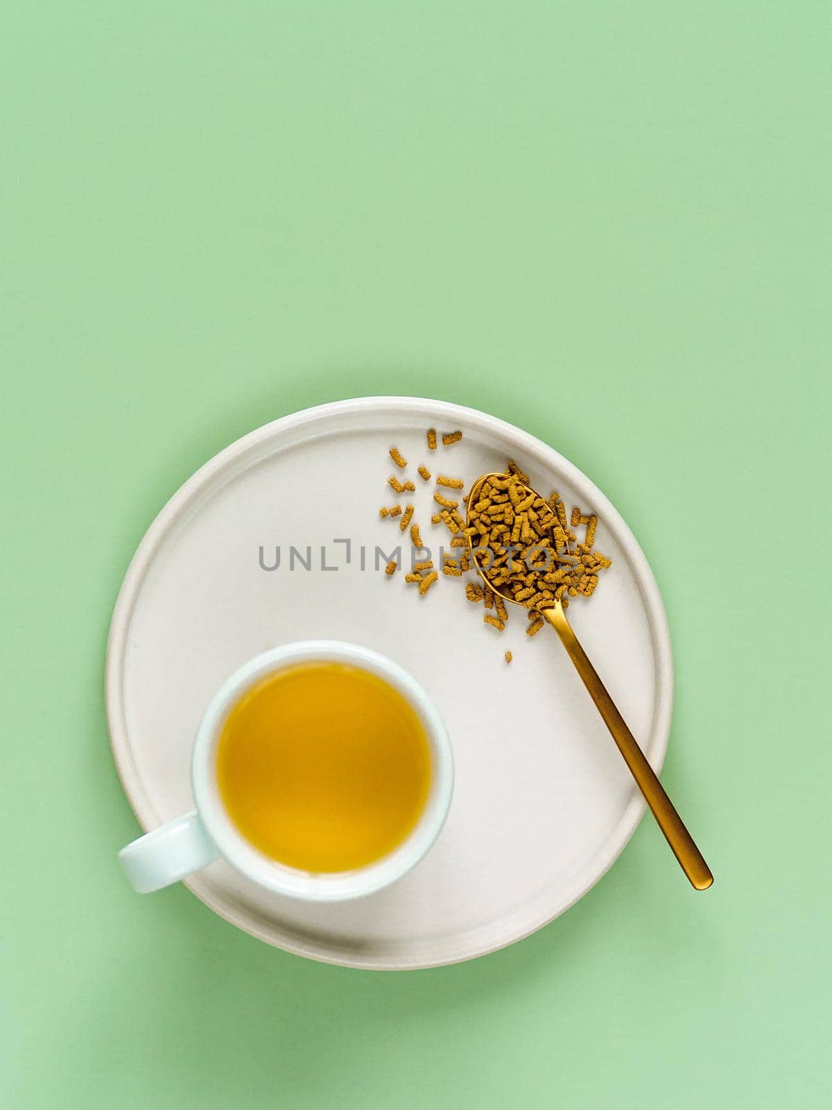 cup of buckwheat tea on light green background. Top view of healthy soba tea and groats in spoon on green paper background. Flat lay. Copy space. Vertical