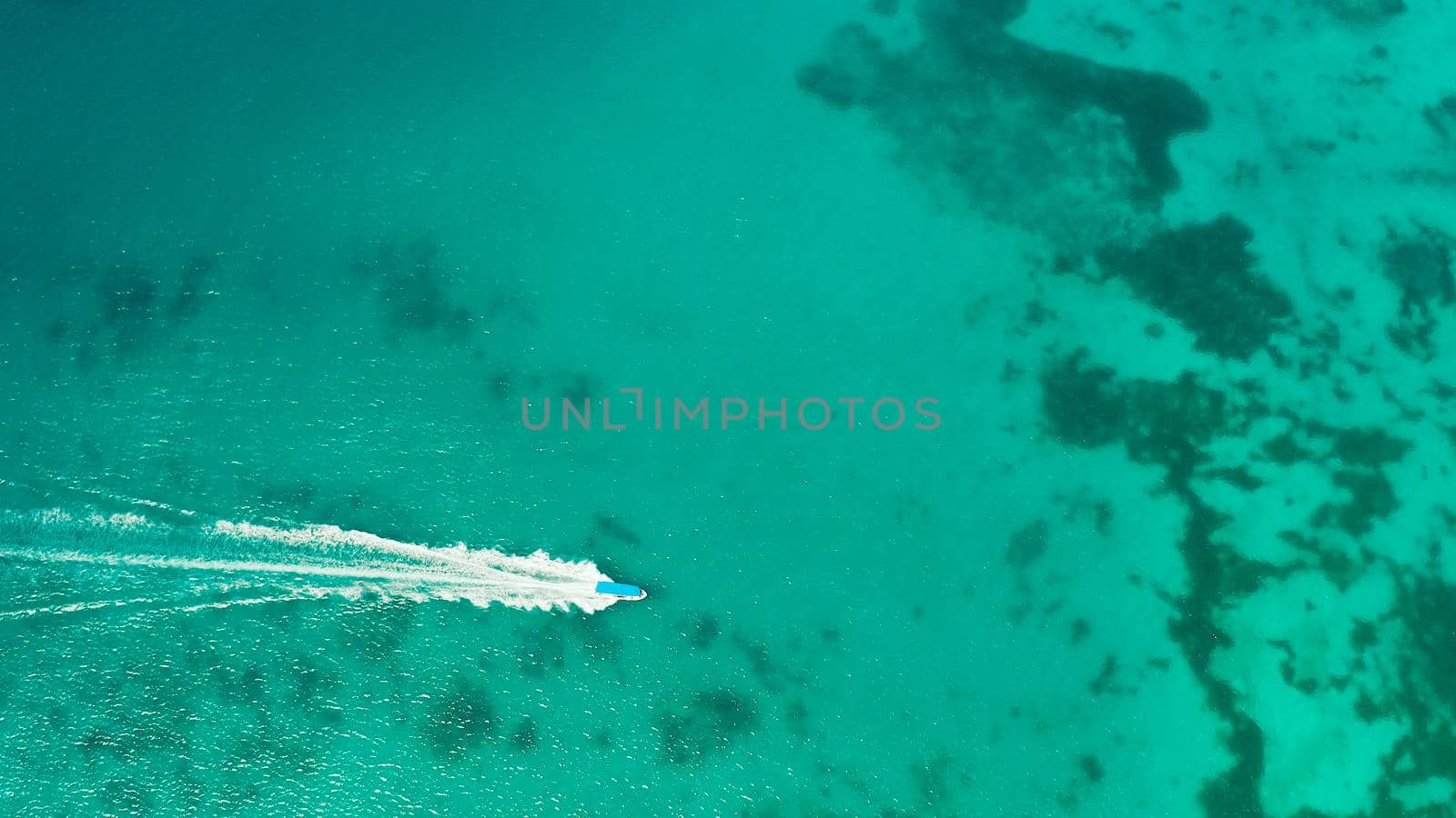 Tourist boats on the surface of the turquoise lagoon, aerial view. Seascape with beach on tropical island. Summer and travel vacation concept. Boracay Island, Philippines