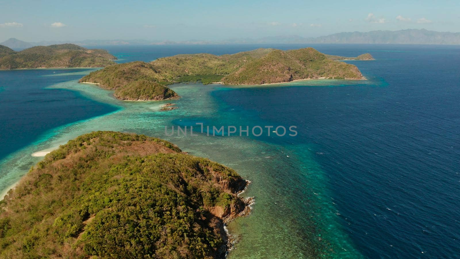 Tropical islands with blue lagoons, coral reef and sandy beach, aerial view. Palawan, Philippines. Islands of the Malayan archipelago with turquoise lagoons.