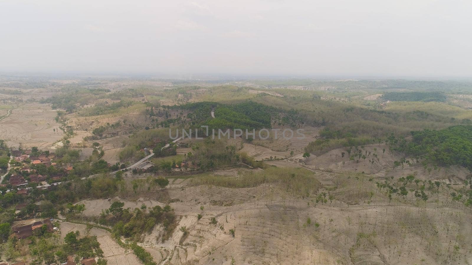 agricultural land in rural areas with farmlands, fields with crops, trees in arid hilly terrain. aerial view growing crops in asia in hilly areas Indonesia.