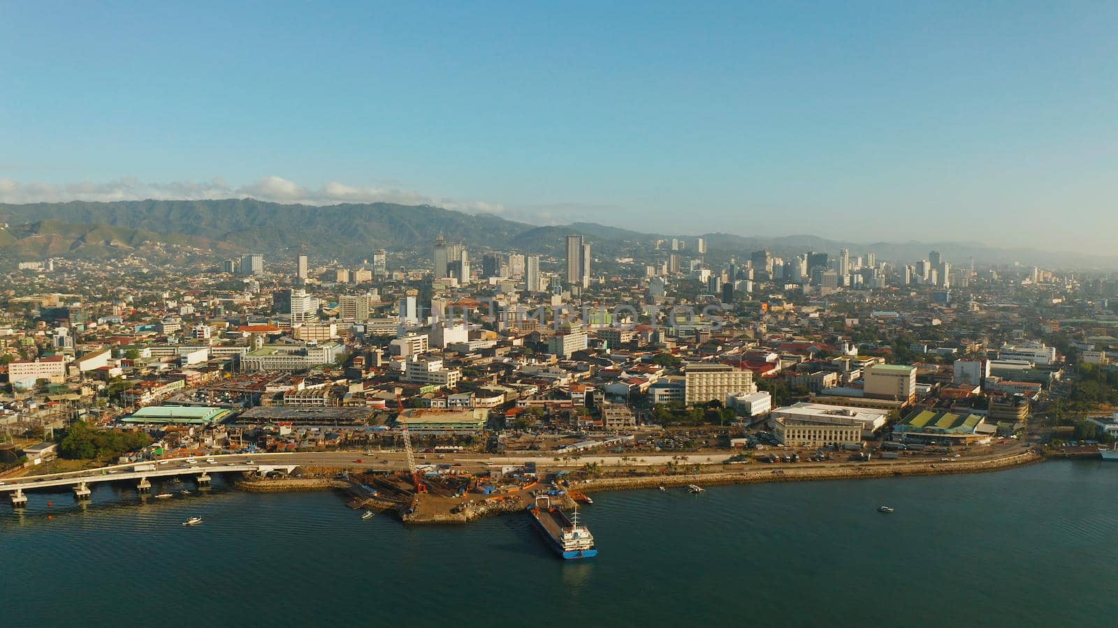 Aerial view of panorama of Cebu city with skyscraper, buildings and seaport with ships and ferries in the early morning. Philippines.