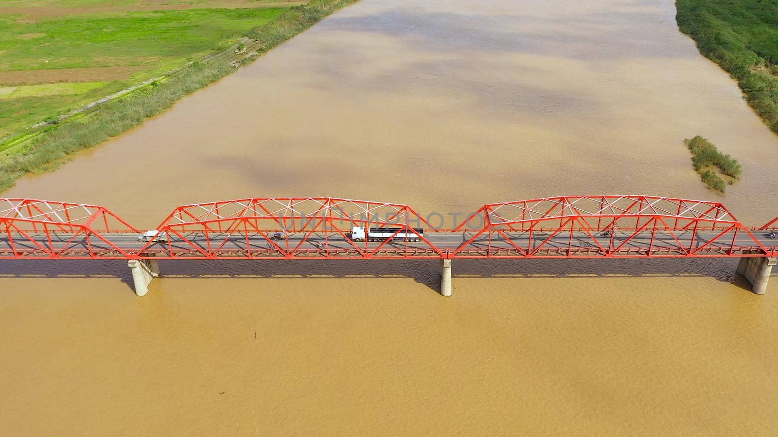 Bridge over the Cagayan River, Philippines, aerial view. Road bridge over a wide river. Cars ride on the bridge. Landscape, agricultural fields near the river.