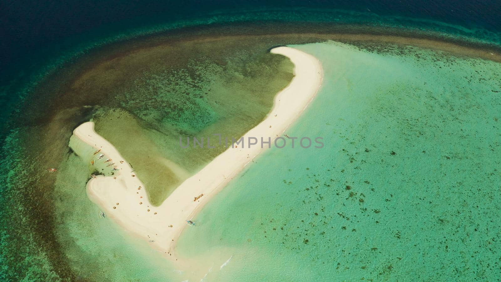 Tropical white island and sandy beach with tourists surrounded by coral reef and blue sea, aerial view. Sandbar Atoll. Island with sand bar and coral reef. Summer and travel vacation concept, Camiguin, Philippines.