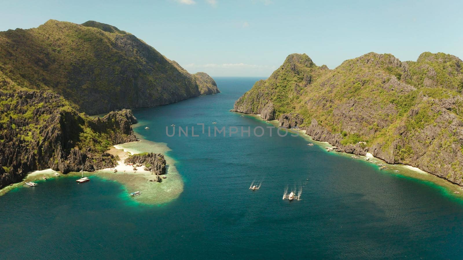 Tropical landscape bay with beach and clear blue water surrounded by cliffs, aerial drone. El nido, Philippines, Palawan. Seascape with tropical rocky islands, ocean blue water. Summer and travel vacation concept
