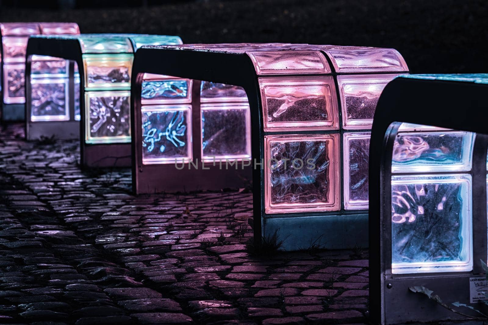 Luminous colorful glass bench in a dark night