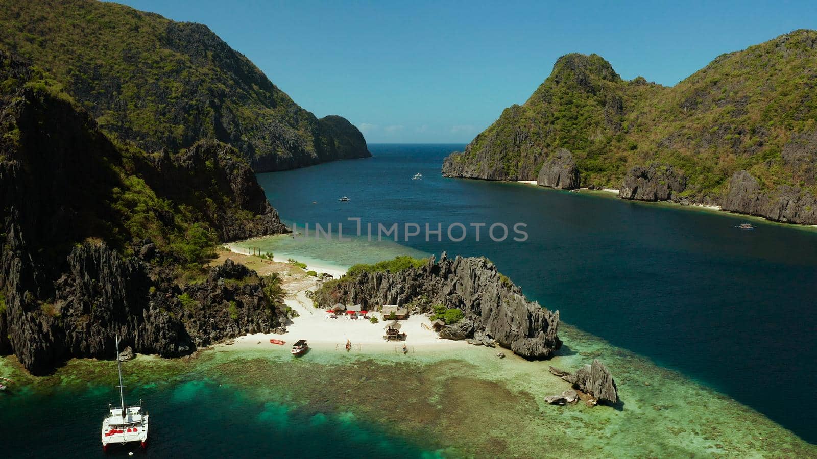 Tropical landscape bay with beach and clear blue water surrounded by cliffs, aerial drone. El nido, Philippines, Palawan. Seascape with tropical rocky islands, ocean blue water. Summer and travel vacation concept