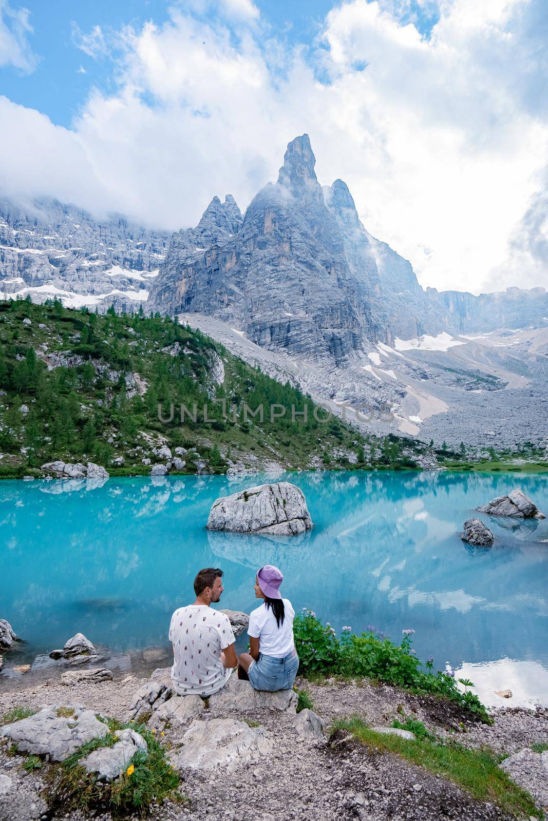 Beautiful Lake Sorapis Lago di Sorapis in Dolomites, popular travel destination in Italy. Blue green lake in Italian Dolomites. Couple hiking in the Dolomites Italy