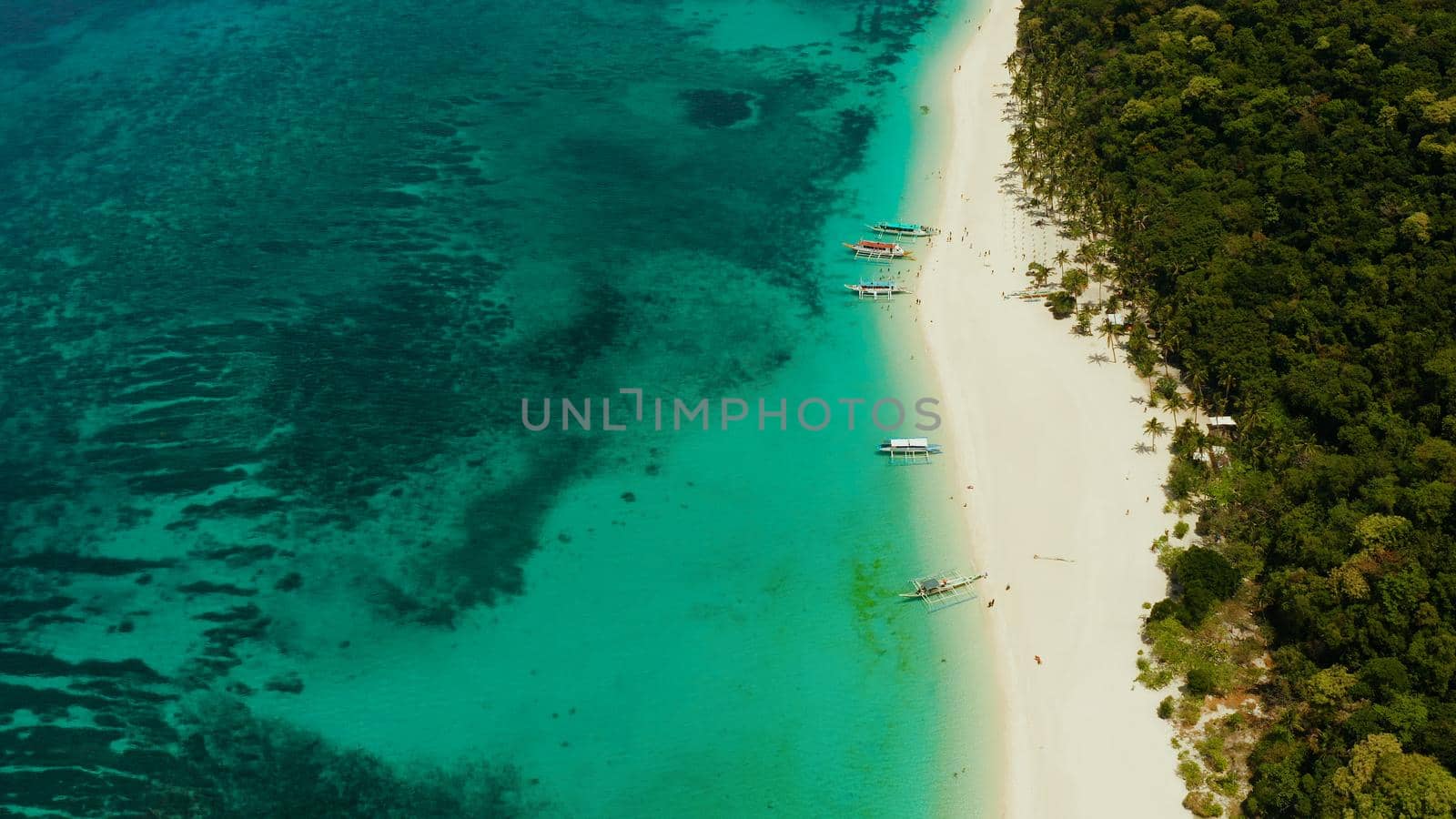 Coast with sandy beach with tourists and clear blue sea top view, Puka shell beach. Boracay, Philippines. Seascape with beach on tropical island. Summer and travel vacation concept.