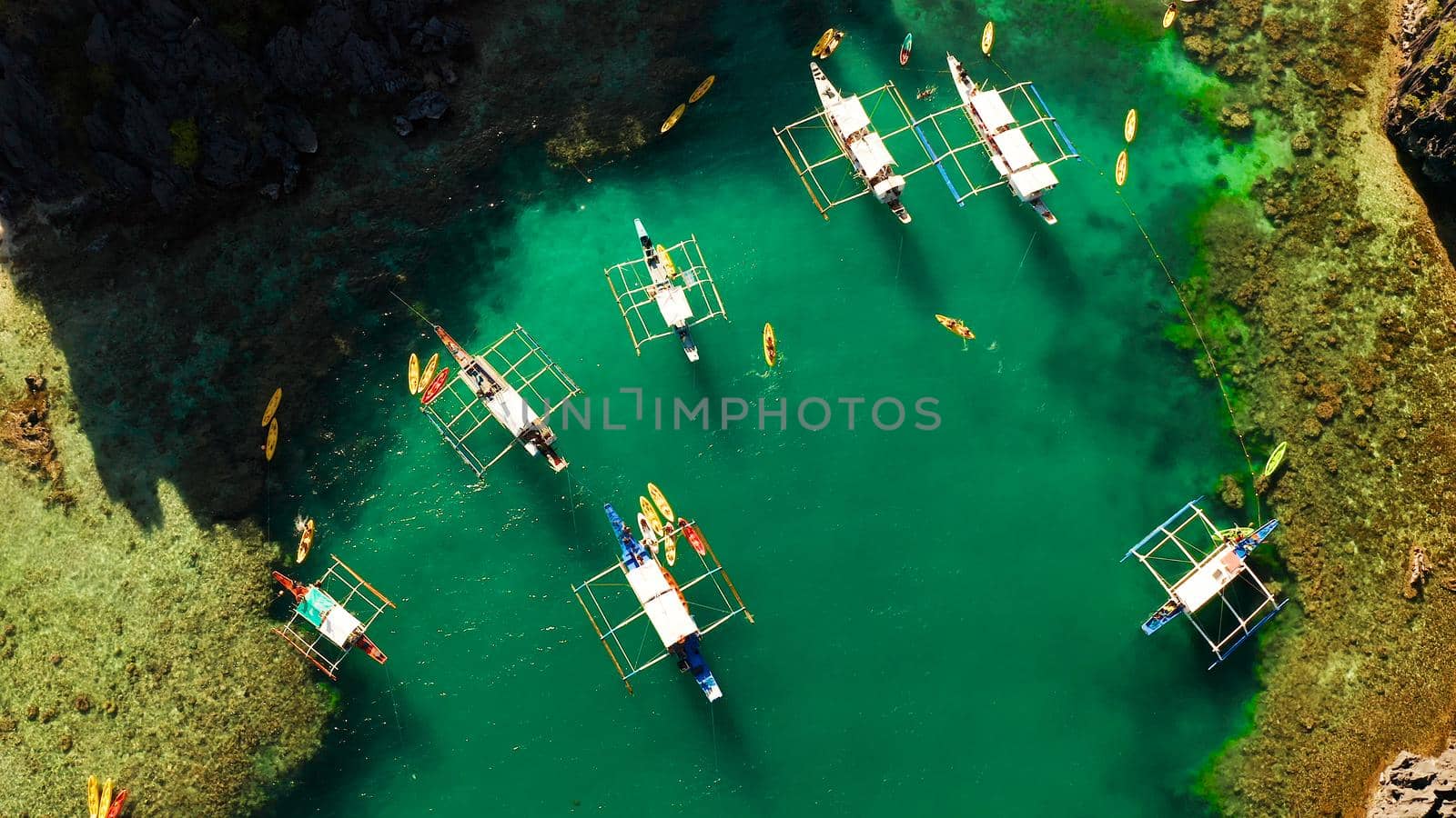 Tourist boats over tropical lagoon and coral reef, aerial view. Small lagoon with turquoise water. El nido, Philippines, Palawan. Summer and travel vacation concept.