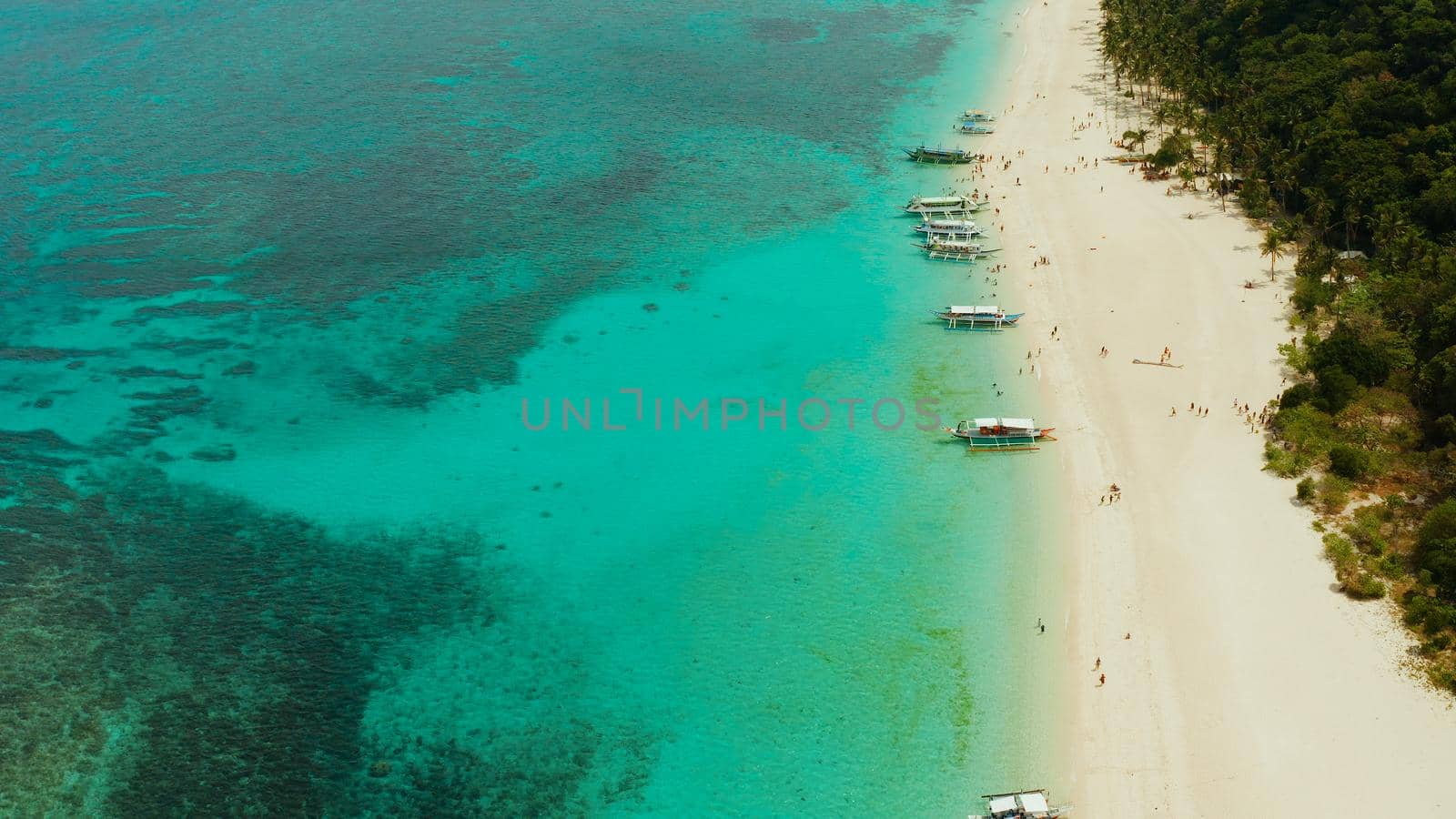 Travel concept: sand beach with tourists and turquoise water on Boracay, Philippines, aerial drone. Seascape with Puka shell beach on tropical island. Summer and travel vacation concept.