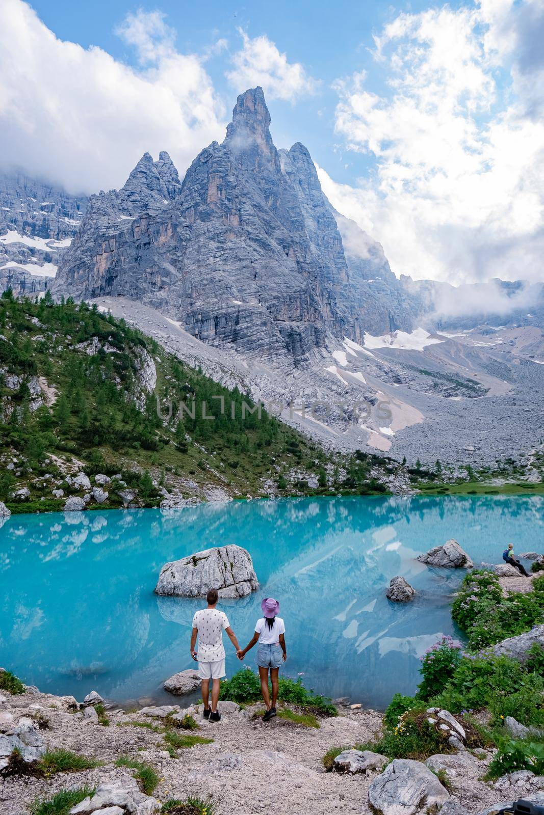 Beautiful Lake Sorapis Lago di Sorapis in Dolomites, popular travel destination in Italy. Blue green lake in Italian Dolomites. Couple hiking in the Dolomites Italy