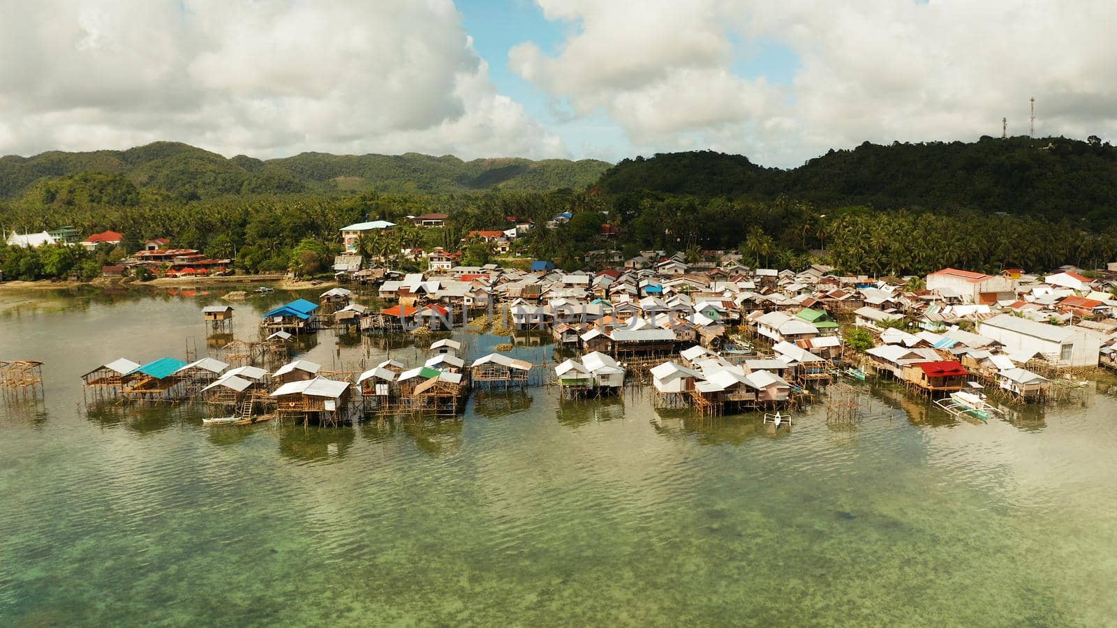 Fishing village with wooden houses standing on stilts in the sea from above. Dapa, Siargao, Philippines.