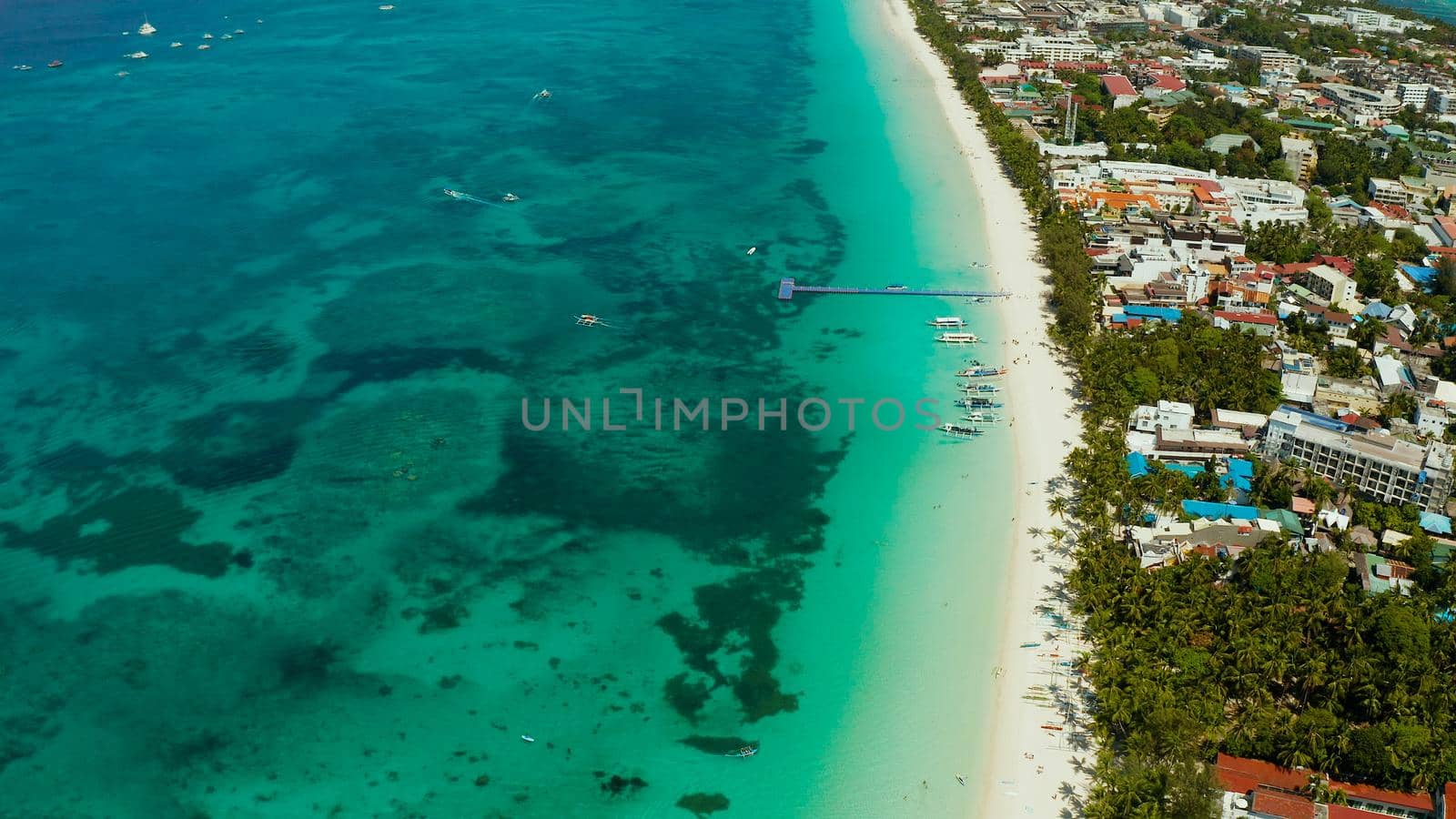 Tropical white beach with tourists and hotels near the blue sea, aerial view. Summer and travel vacation concept.