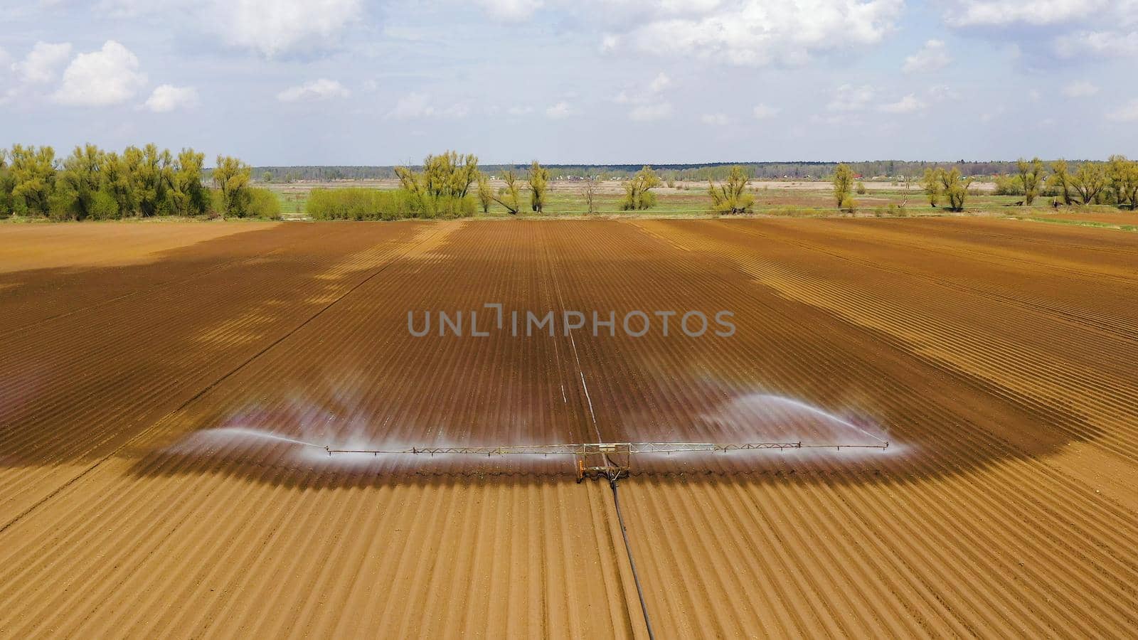 aerial view crop irrigation machine using center pivot sprinkler system. An irrigation pivot watering agricultural land. Irrigation system watering farm land.