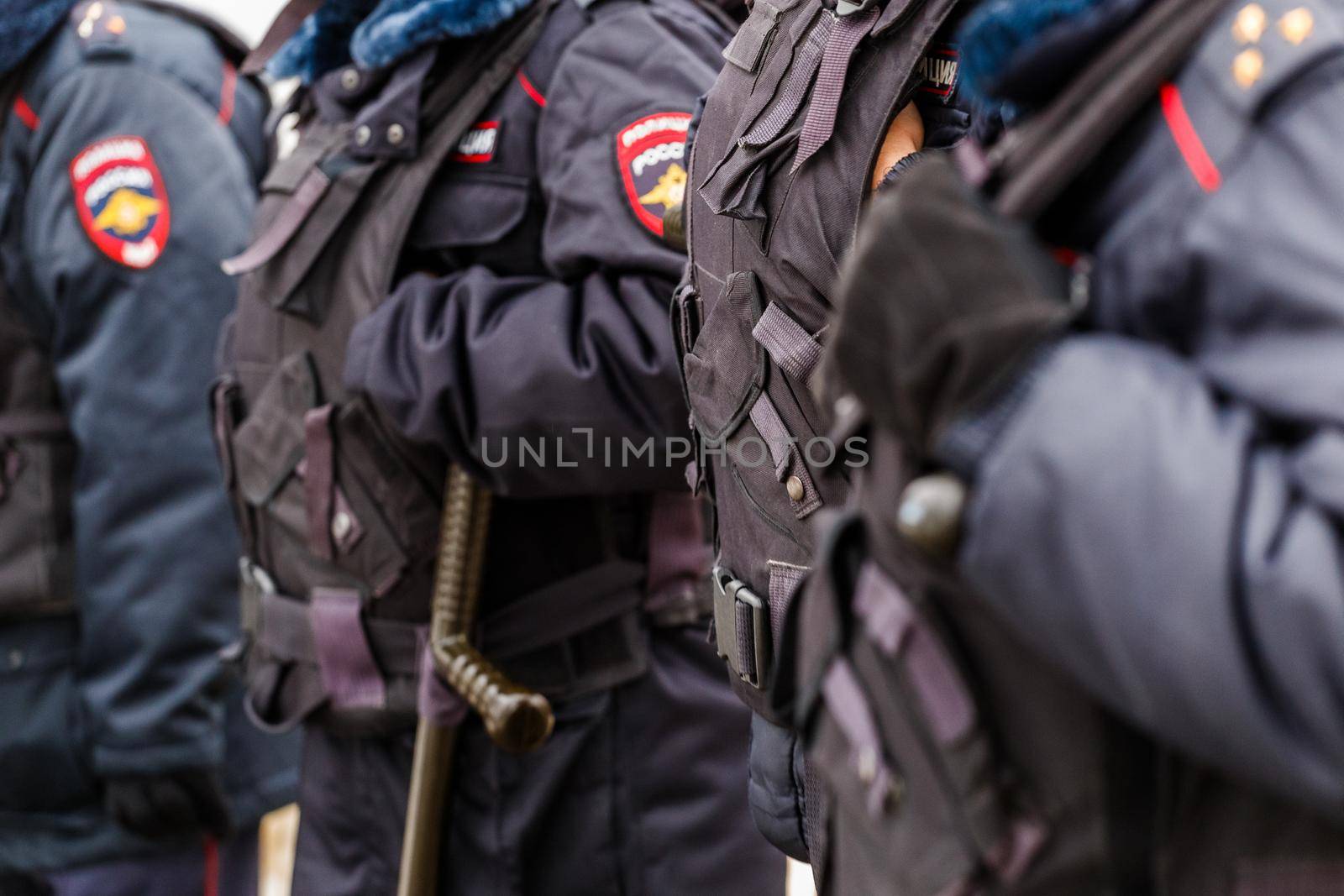 Tula, Russia - January 23, 2021: Police officers in black uniform with bulletproof vests - close-up view on black gloves with background blur.
