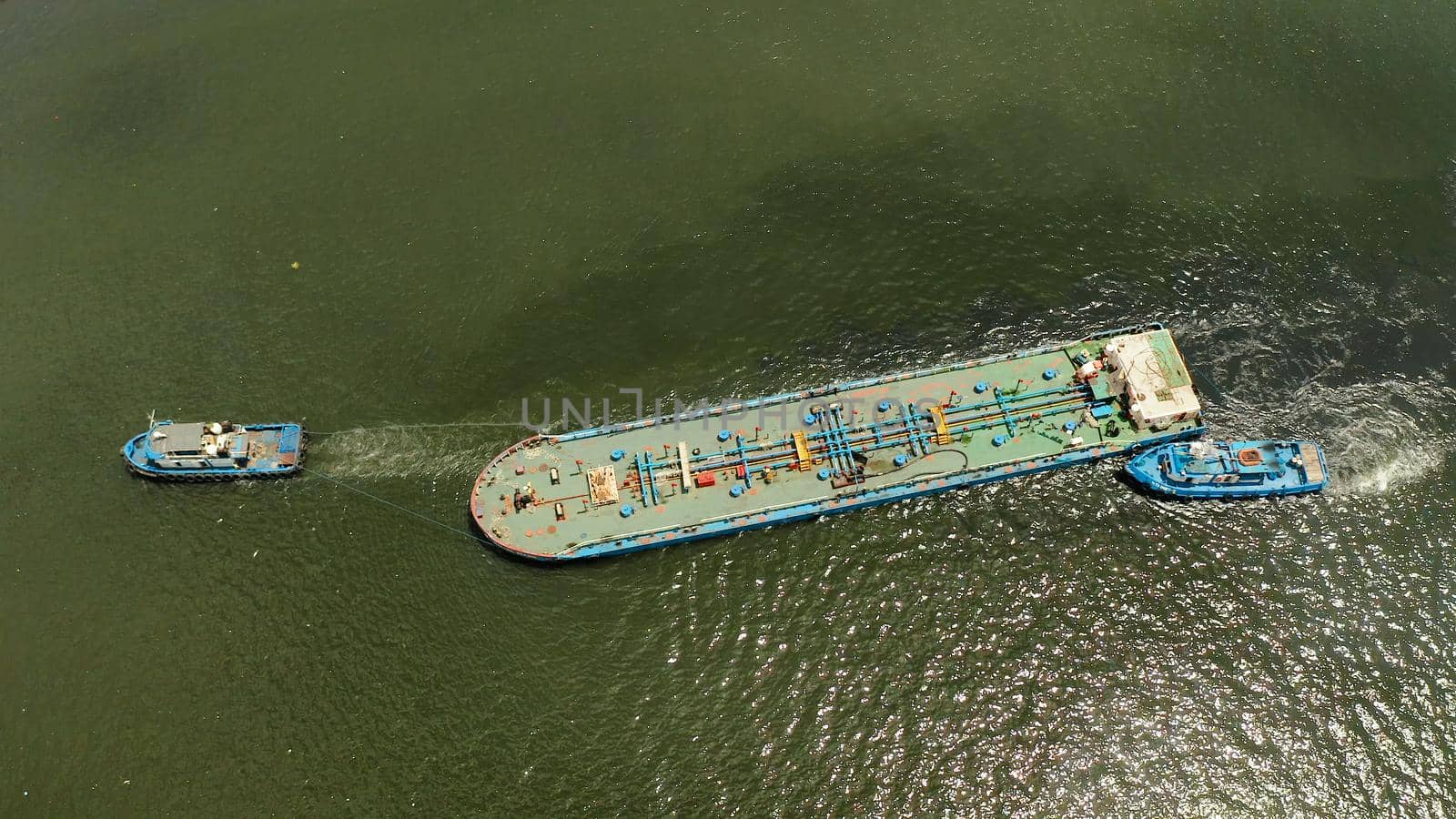 Tugs pulling heavy barge on the river top view. Tugs and cargo ship on the river.