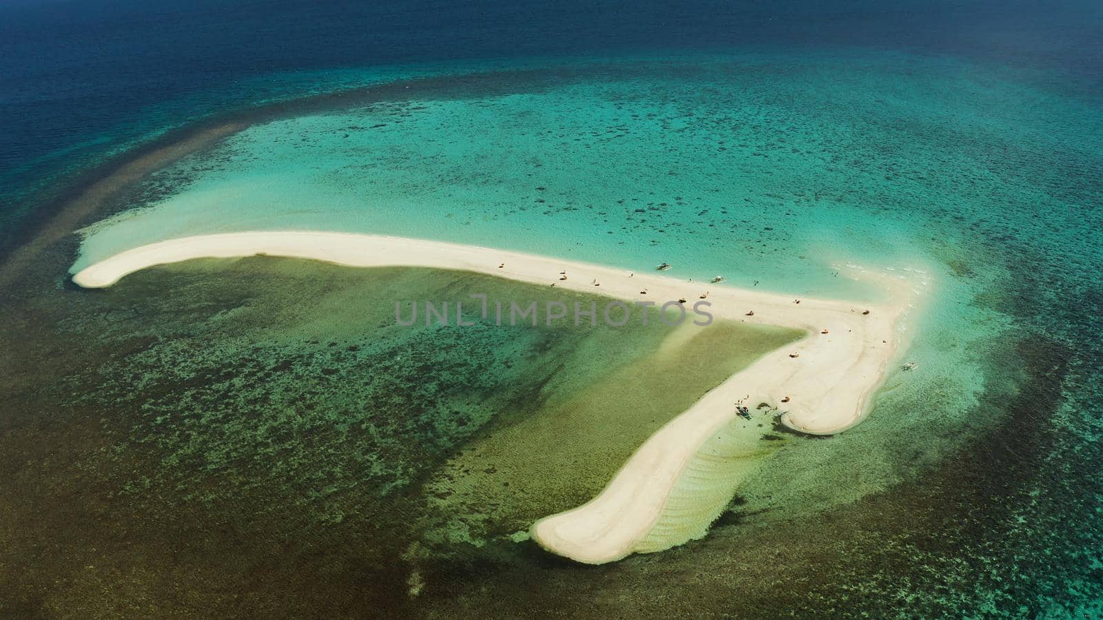 Tropical white island and sandy beach with tourists surrounded by coral reef and blue sea, aerial view. Sandbar Atoll. Island with sand bar and coral reef. Summer and travel vacation concept, Camiguin, Philippines.