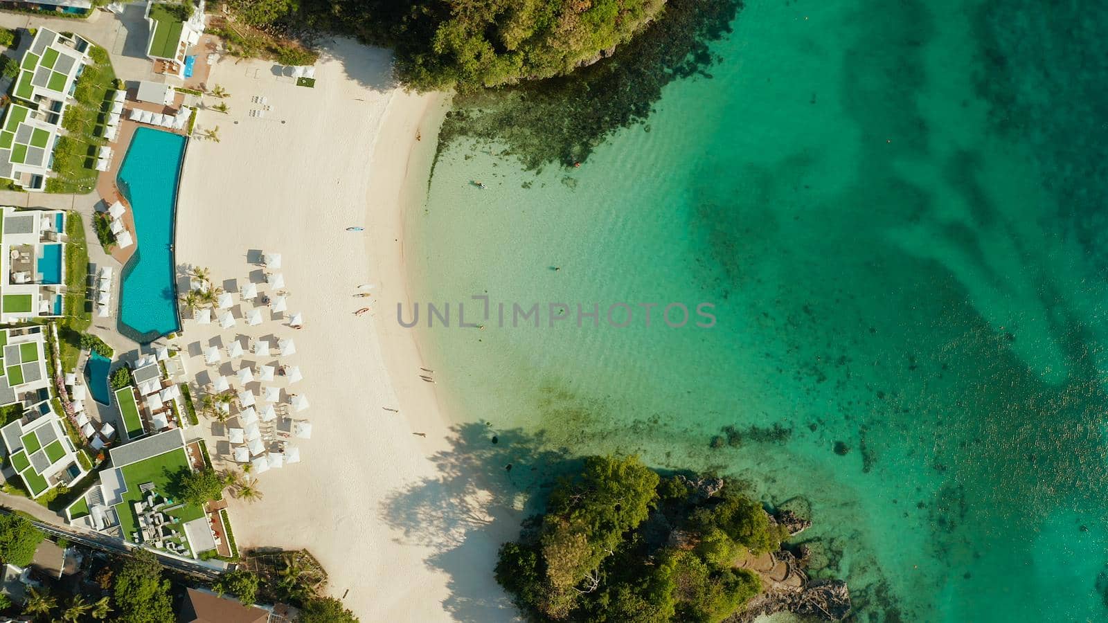 Cove with white beach in blue lagoon with turquoise waters, aerial view. Seascape with beach on tropical island. Summer and travel vacation concept.