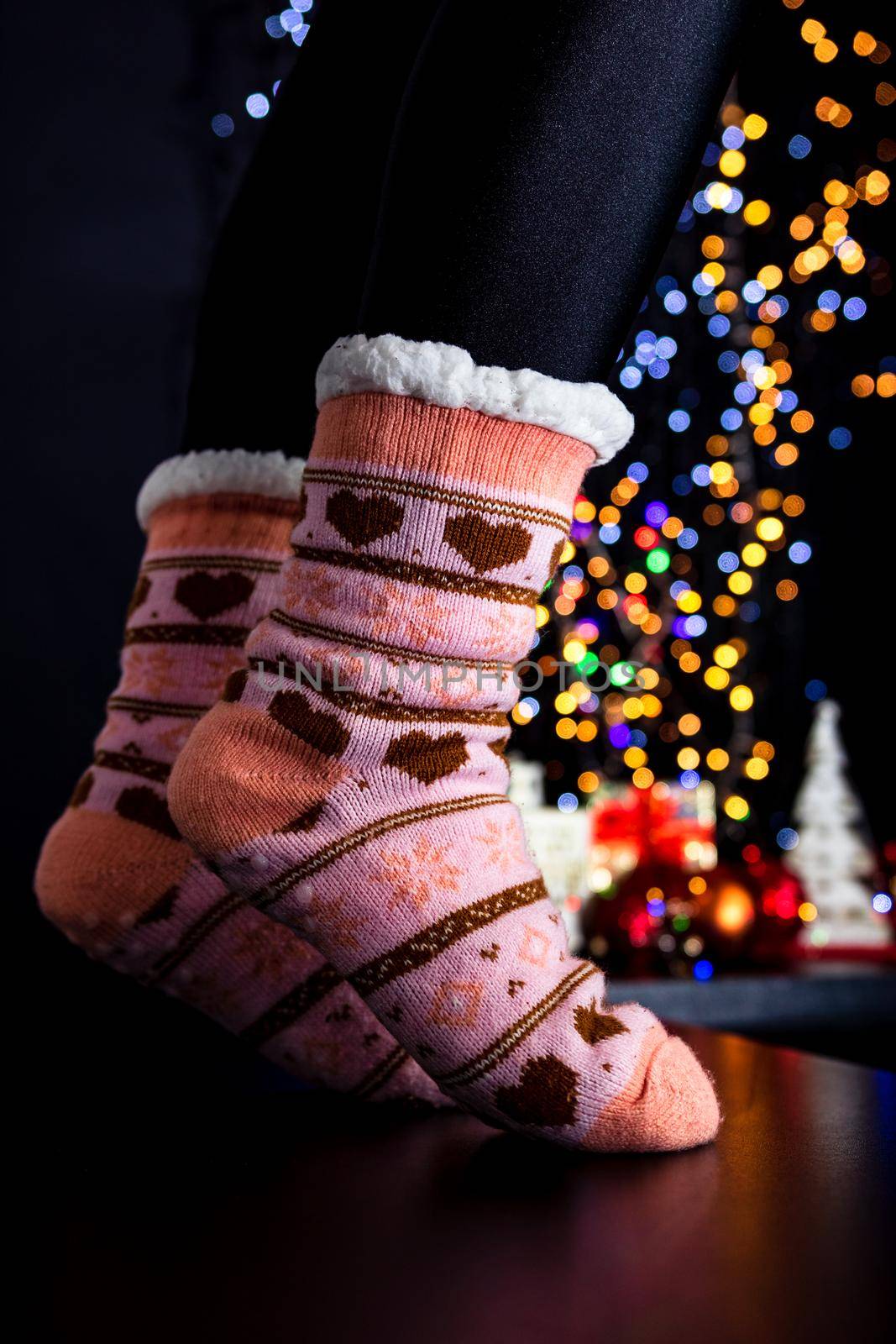 Female legs in Christmas colorful socks near Christmas tree. by vladispas