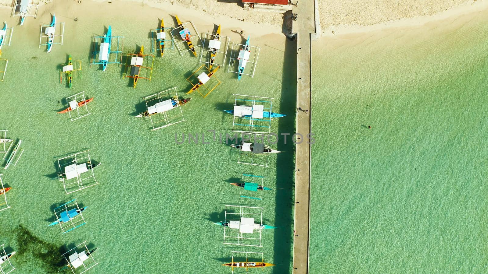Boats on the tropical beach at the long pier awaiting tourists, General Luna, Siargao.