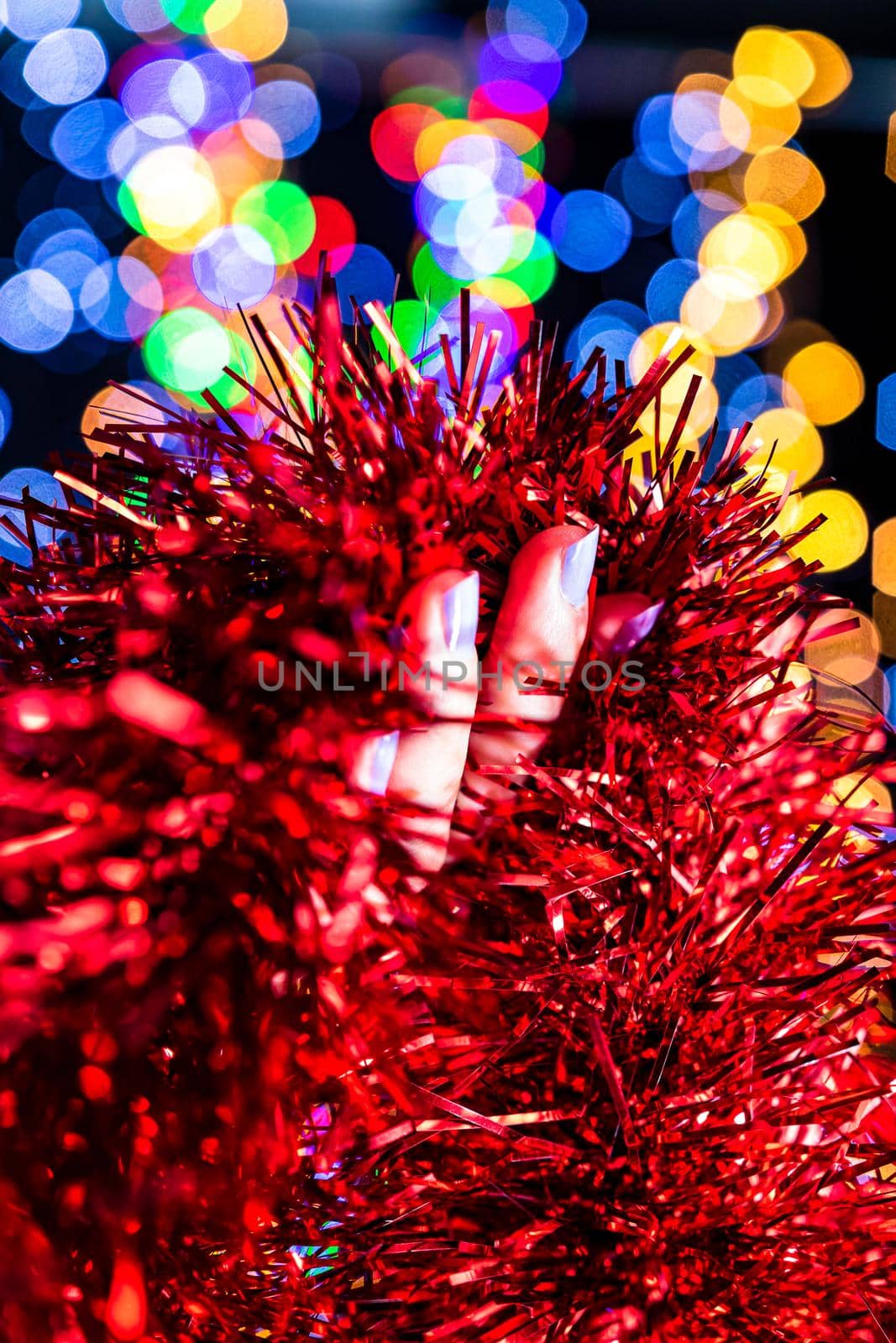 Holding Christmas garland decoration isolated on background with blurred lights. December season, Christmas composition.