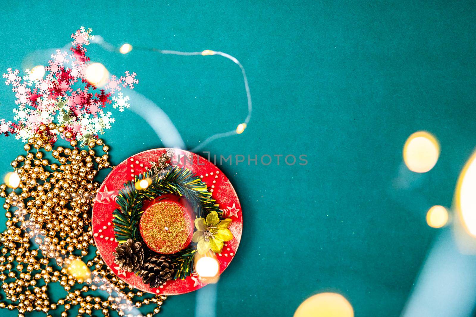 Christmas lights over a december season composition with ornaments and decorations. Top view with copy space on green background.