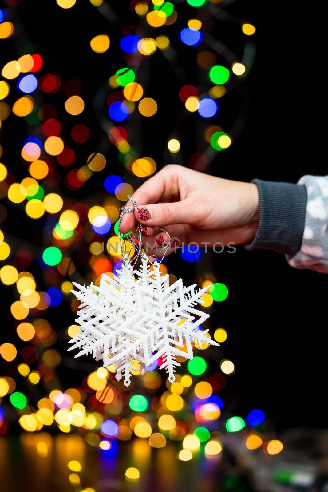 Woman's hands hold christmas decoration. Christmas and New Year holidays background, winter season with Christmas ornaments and blurred lights