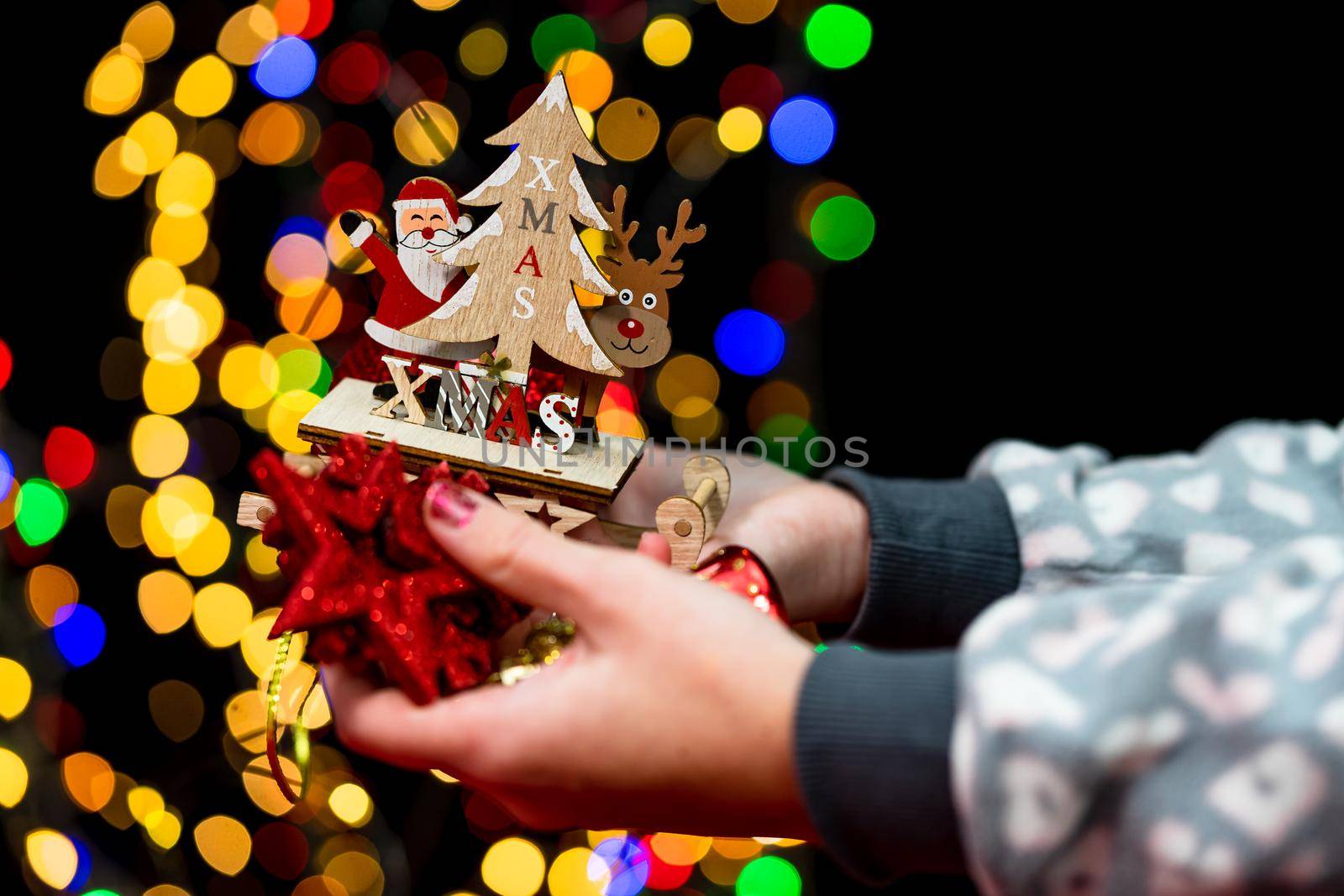 Woman's hands hold christmas decoration. Christmas and New Year holidays background, winter season with Christmas ornaments and blurred lights