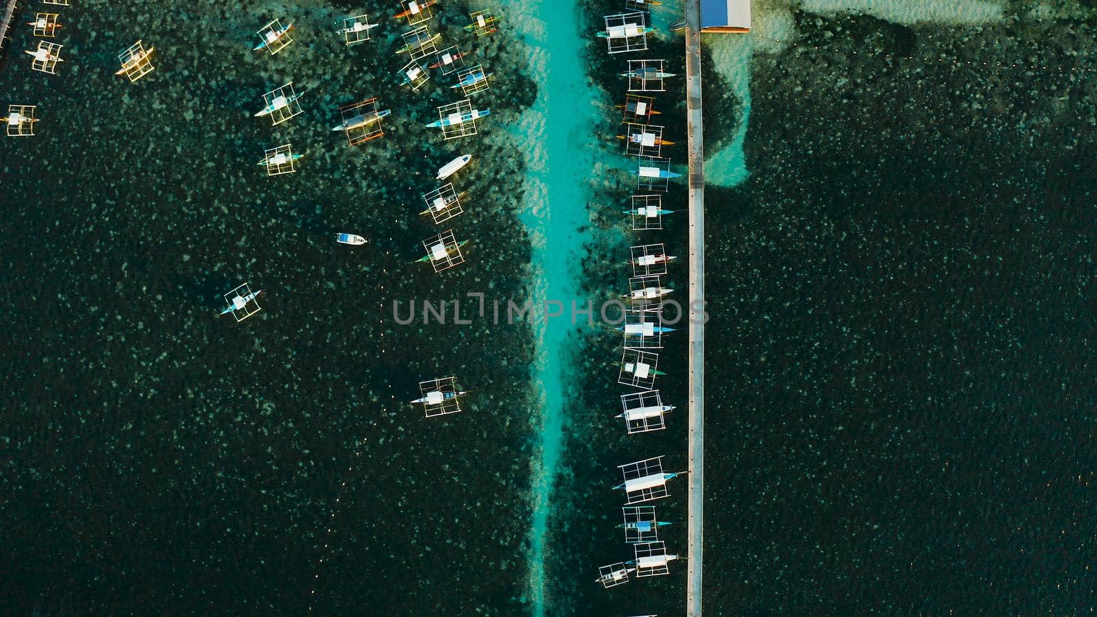 Long pier with moored boats in the morning, aerial view. General Luna, Siargao island.