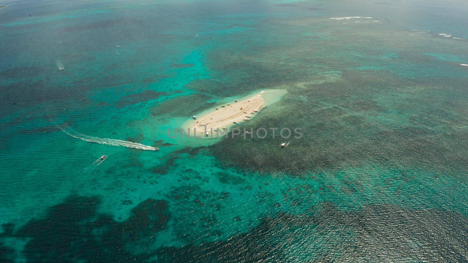 Tropical white island and sandy beach with tourists surrounded by coral reef and blue sea, aerial view. Naked Island, Siargao. Summer and travel vacation concept