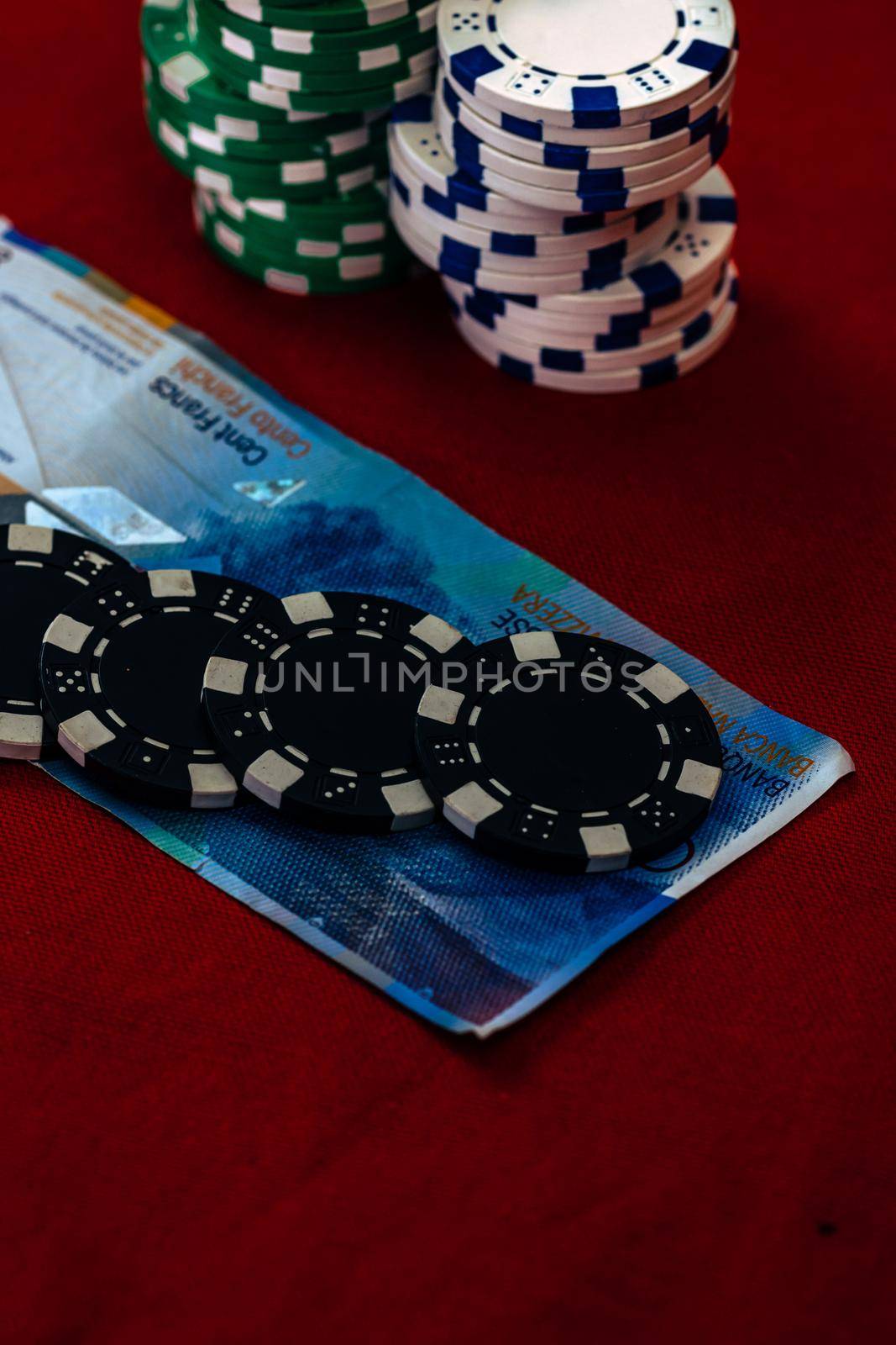 Stacks of poker chips with money on red background, CHF currency by vladispas