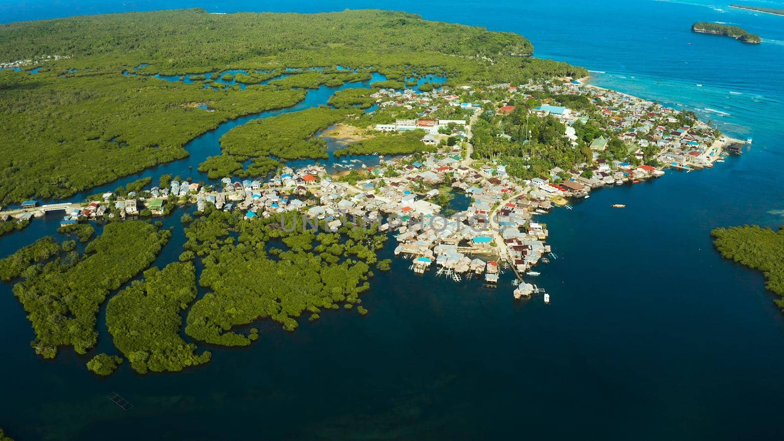 Town in wetlands and mangroves on the ocean coastline from above. Siargao island, Philippines.