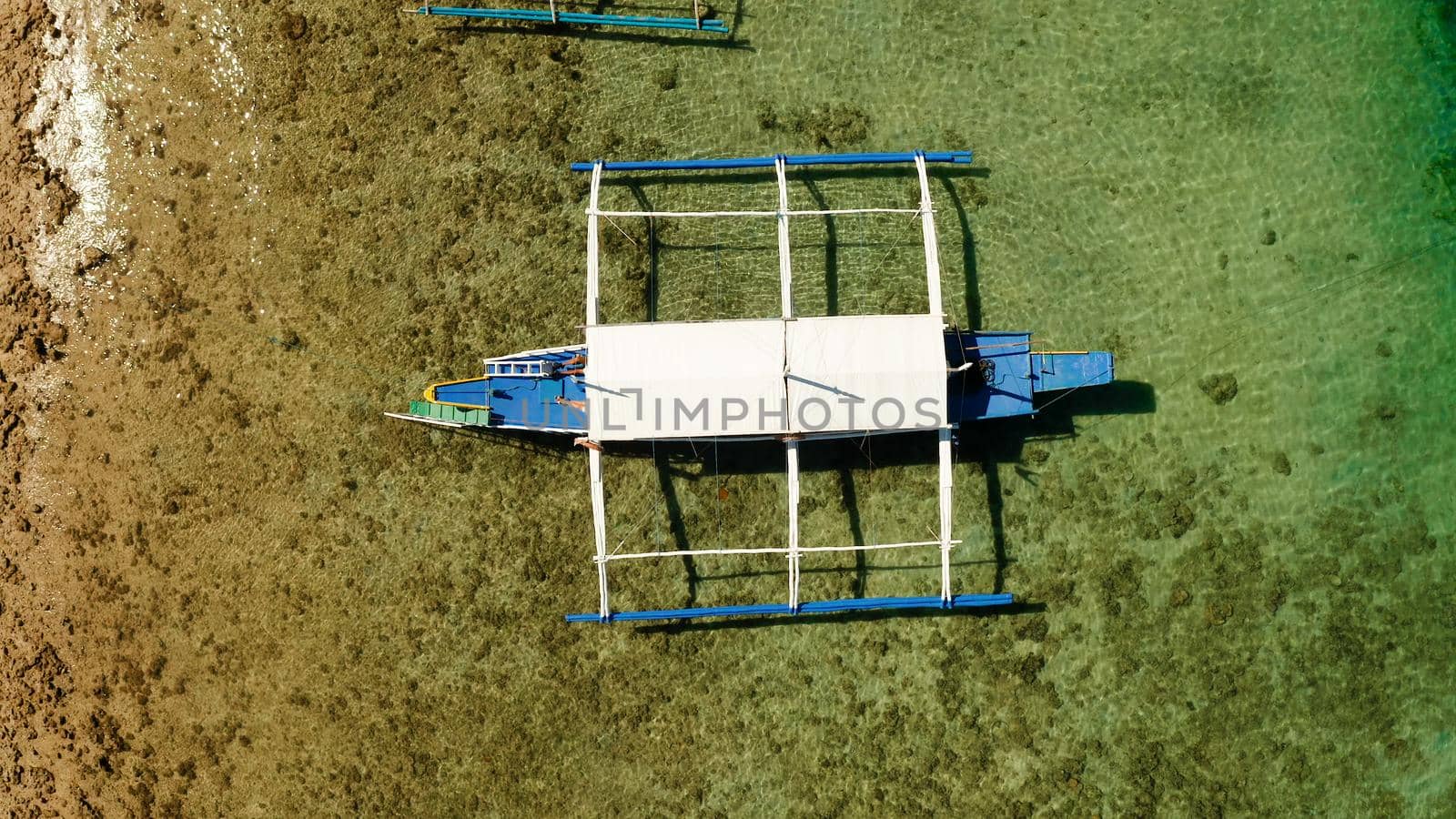 Traditional Philippine boat on the surface of the azure water in the lagoon. Top view of boat from drone.