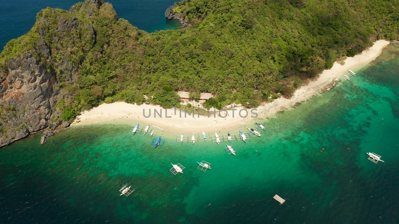 Aerial drone tropical island with sandy beach, green foliage and palm trees. Lagoon with azure and clear water. Helicopter Island in El Nido, Palawan Philippines. Summer and travel vacation concept