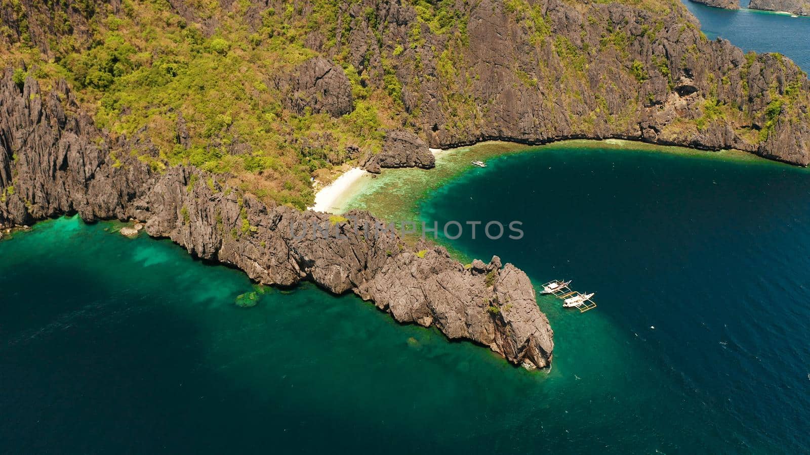 Aerial drone tropical landscape bay with beach and clear blue water surrounded by cliffs. El nido, Philippines, Palawan. Seascape with tropical rocky islands, ocean blue water. Summer and travel vacation concept