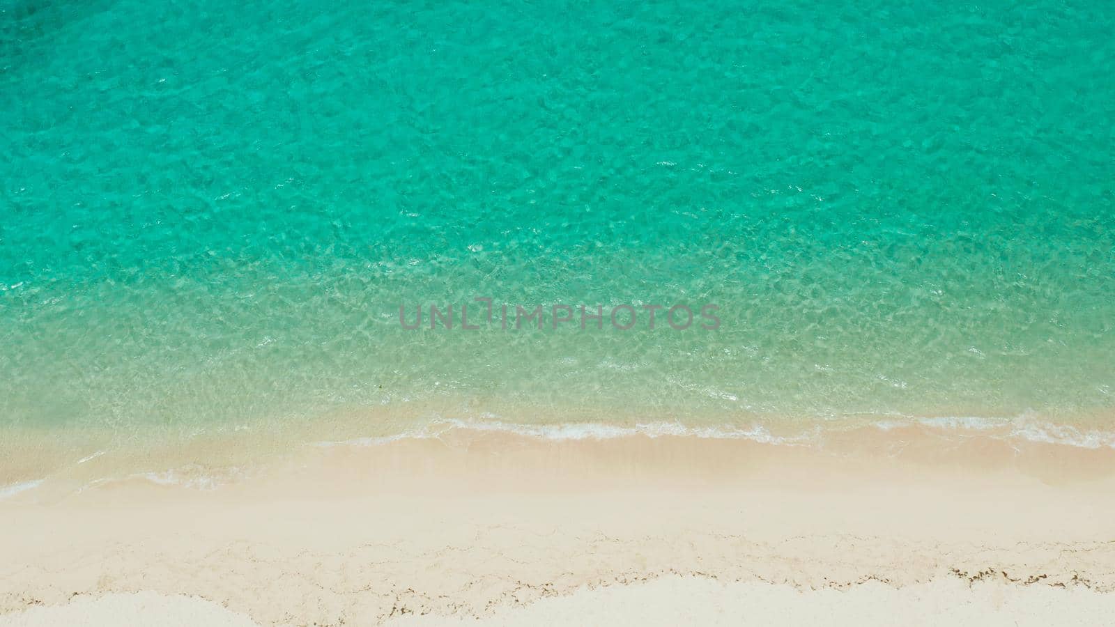 Tropical sandy beach with wave and turquoise water,copy space for text, aerial view. Sea water surface in lagoon. Transparent turquoise ocean water surface. Background texture