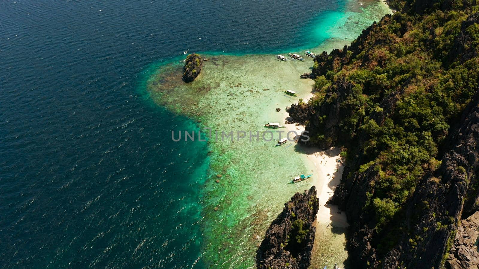 Aerial drone tropical landscape bay with beach and clear blue water surrounded by cliffs. El nido, Philippines, Palawan. Seascape with tropical rocky islands, ocean blue water. Summer and travel vacation concept