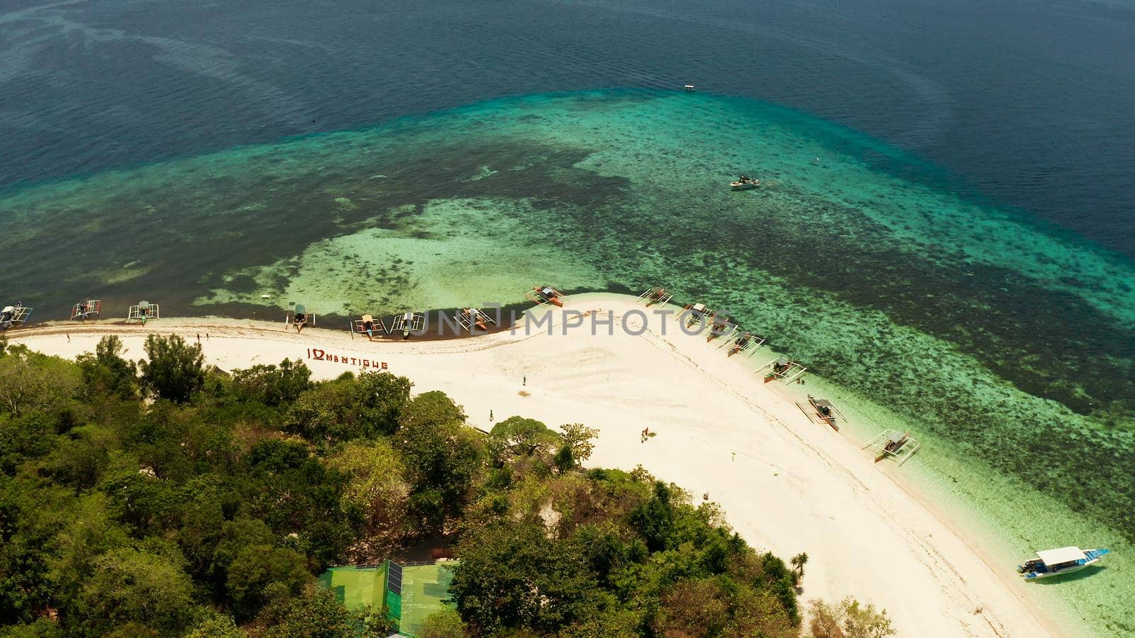 Tropical island and sandy beach surrounded by atoll coral reef and blue sea, aerial view. Small island with sandy beach. Summer and travel vacation concept, Mantigue Philippines Mindanao
