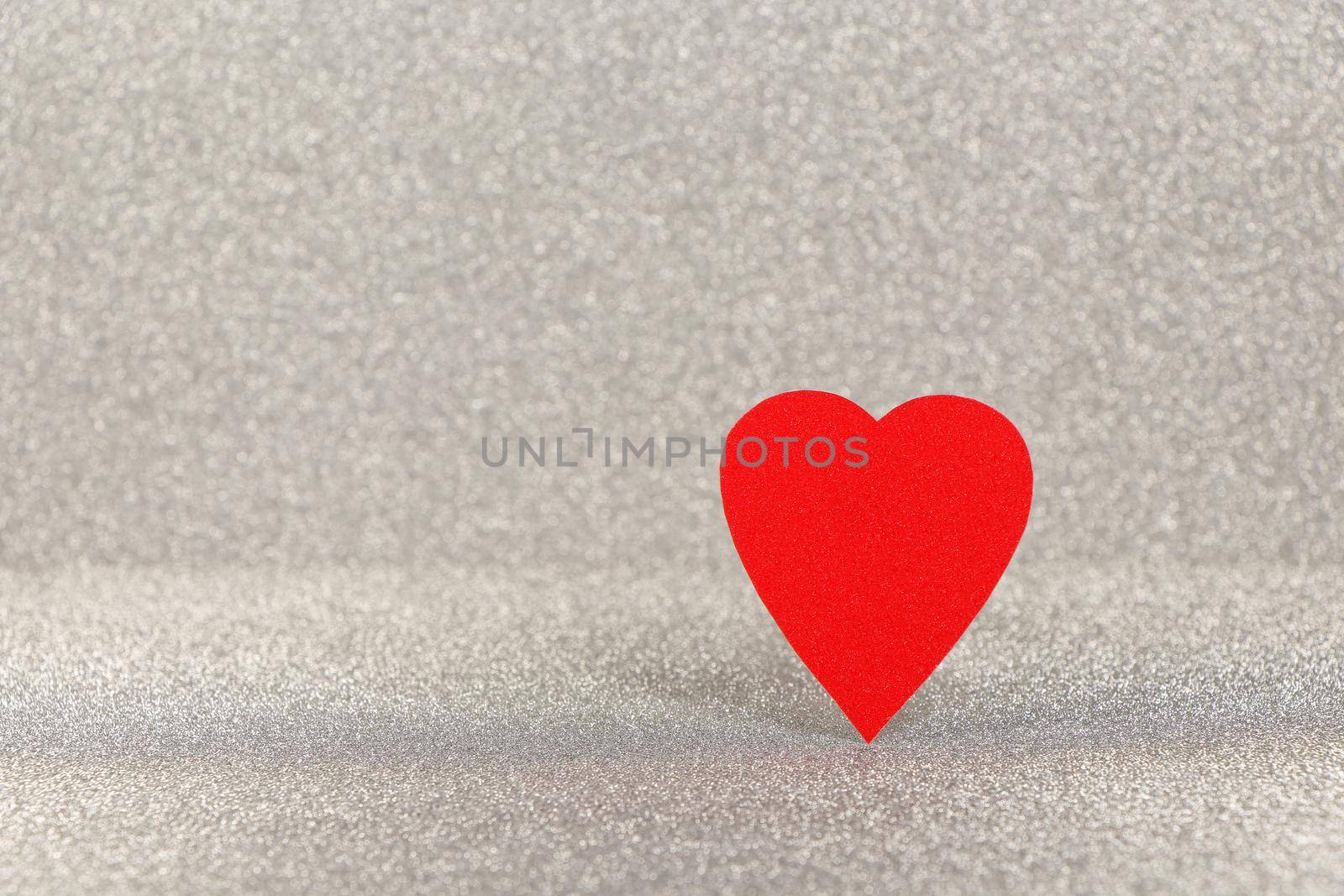 Saint Valentine's day vibrant red heart standing on bright textured silver