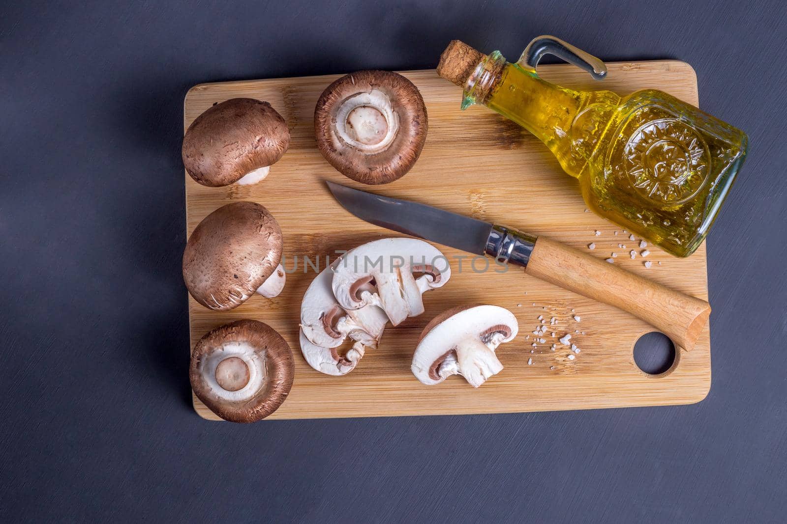 Still life of mushrooms champignons on a cutting board with knife and olive oil by galinasharapova