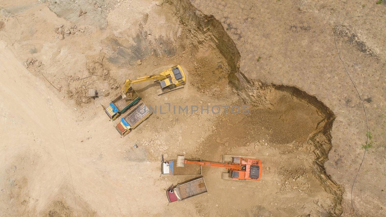 excavator at construction site cuts hill and loads truck with earth. aerial view Heavy machinery prepares the countryside for construction. Excavators are been used in large and small scale constructions Indonesia