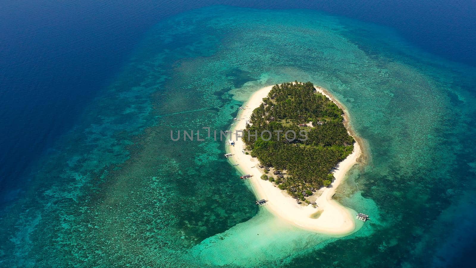 Tropical island with a beach and palm trees. Beautiful lagoon and white sandy beach, aerial view. Digyo Island.